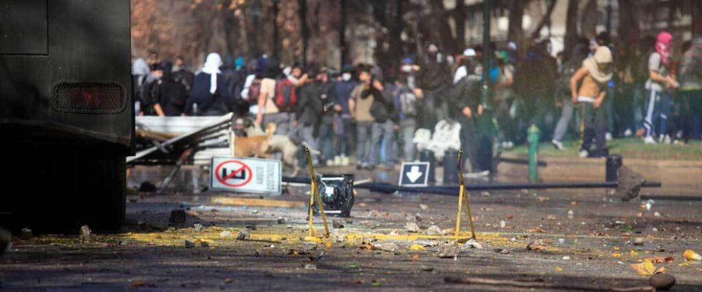 Debris on a city street with rioters nearby